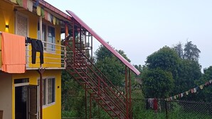 Um edifício amarelo com uma escadaria vermelha que leva a uma varanda.