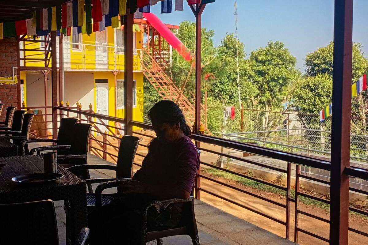A restaurant with outdoor seating, a brick wall, and colorful flags.