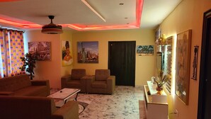 Una sala de estar con sofá, sillas, una mesa de centro y un mueble de televisión con adornos.
