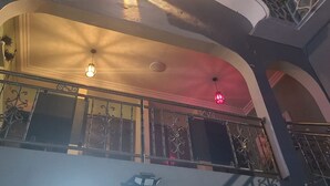 Un balcón con barandillas de metal ornamentadas y un techo con lámparas decorativas.