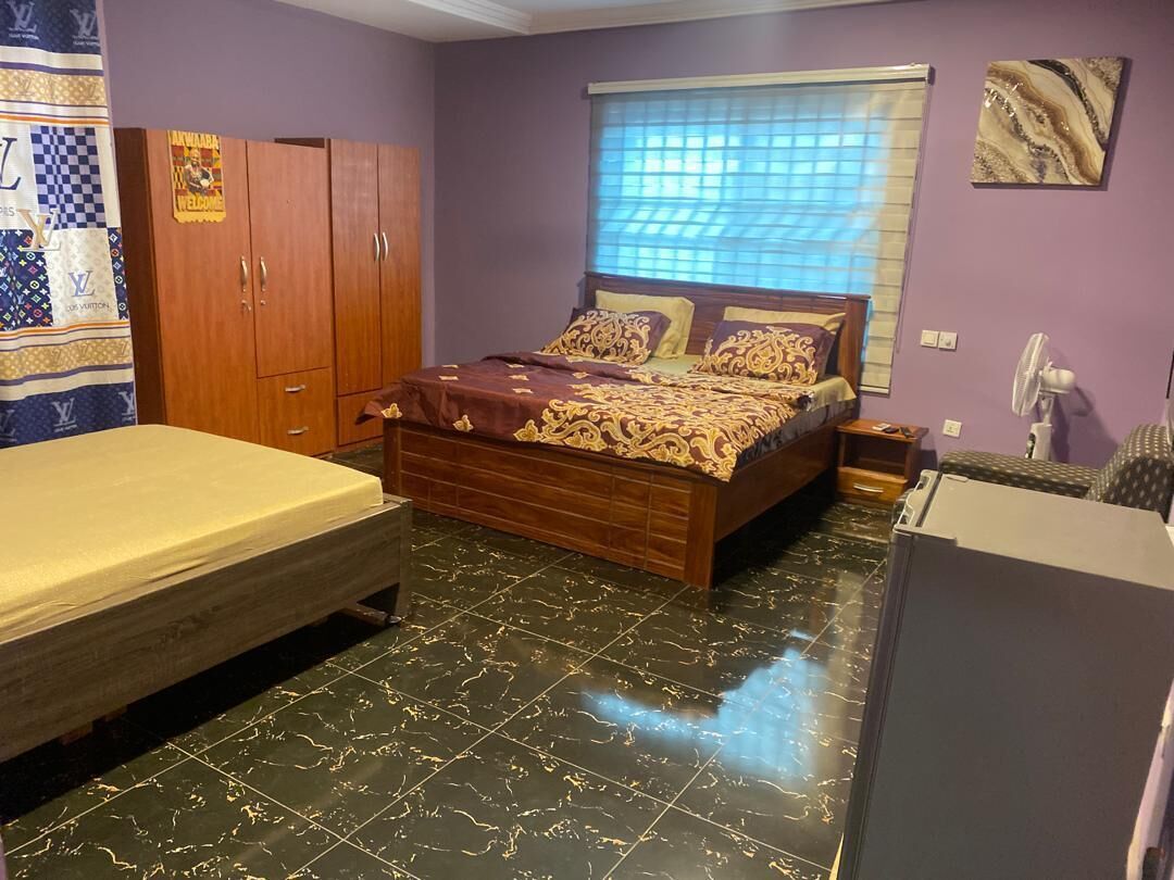 Un dormitorio con cama, armario, escritorio y ventana con persianas.