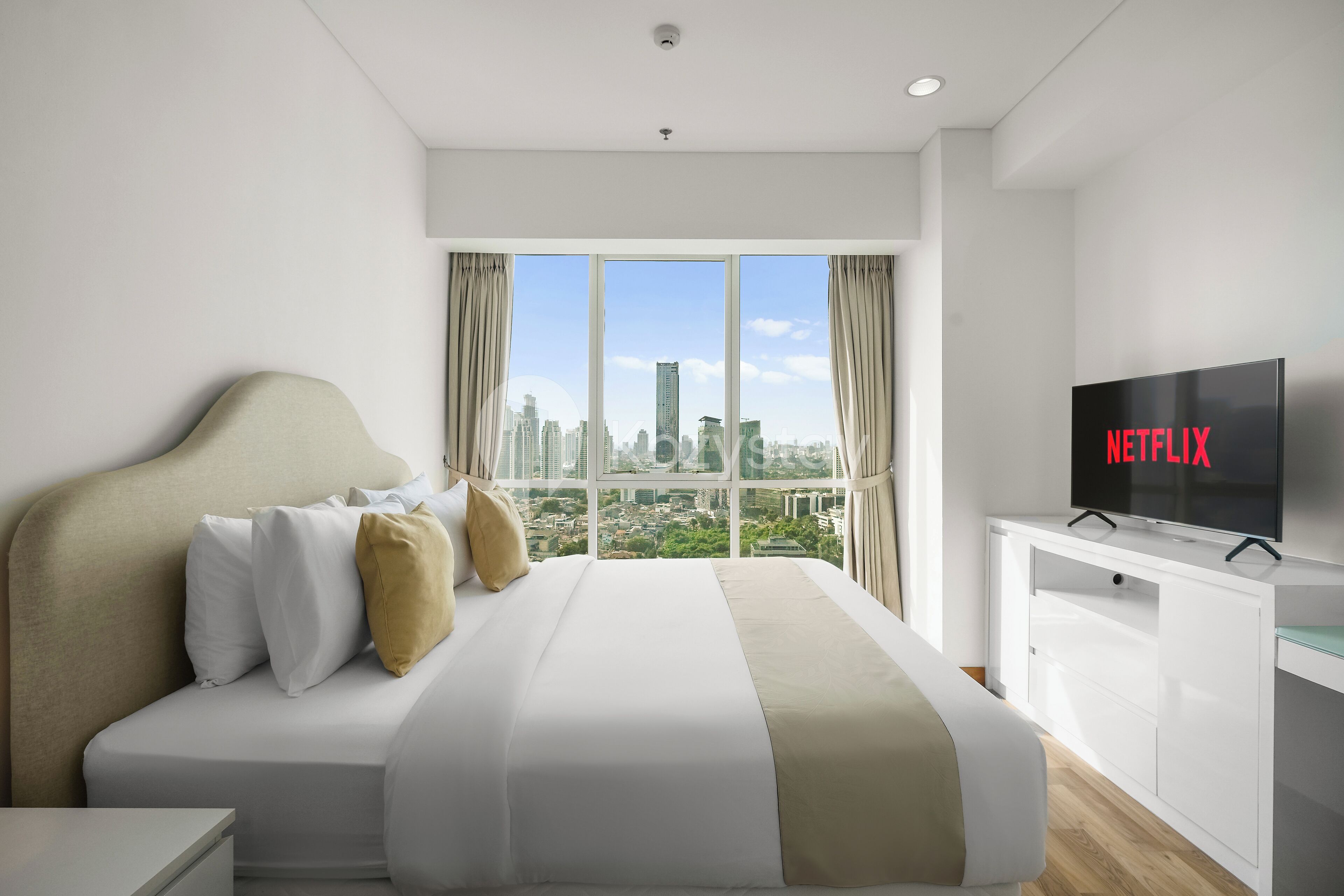 Une chambre d’hôtel avec un grand lit, une télévision et une vue sur la ville.
