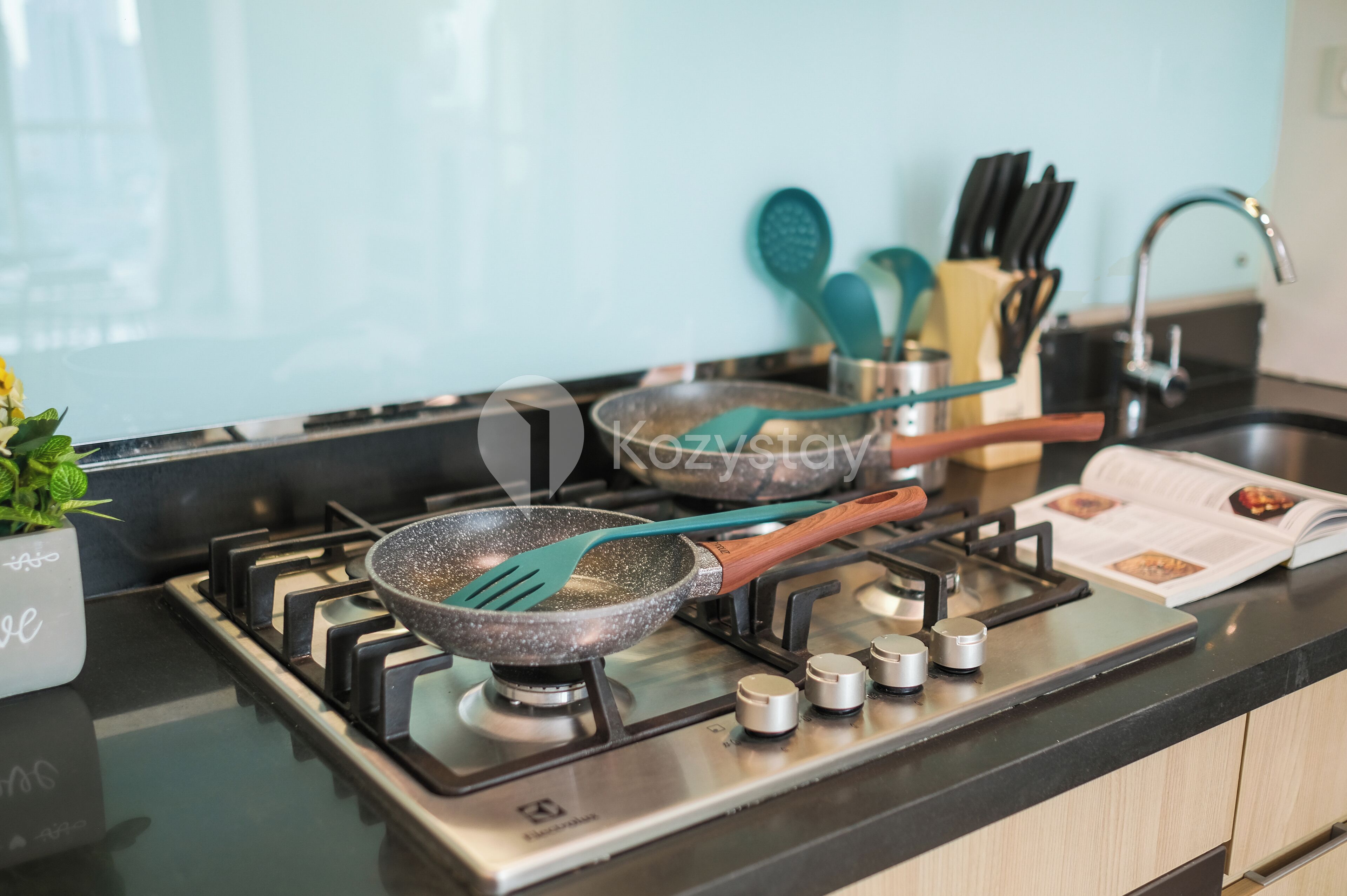 Una cocina con estufa a gas, una sartén y diferentes utensilios.