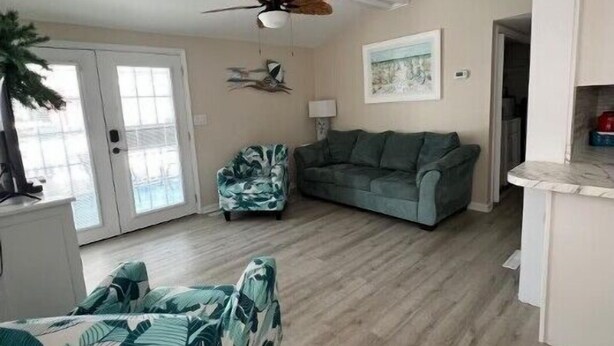 Un salon doté d’un ventilateur de plafond, d’un canapé, d’un fauteuil et d’un coin repas avec un comptoir.