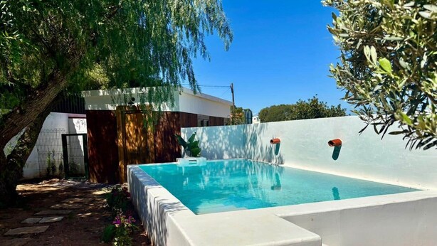 A rectangular swimming pool with a white border, surrounded by a white wall and a tree. - Rincón Vacacional Les Rotes 53 · Near de sea (Unknown)