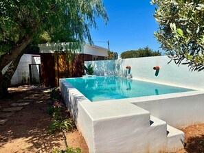 A rectangular swimming pool with a white border, surrounded by a white wall and a tree. - Rincón Vacacional Les Rotes 53 · Near de sea (Unknown)