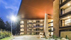 Un edificio de varios pisos con un camino curvo y una entrada bien iluminada.