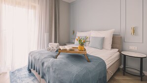 A bedroom with a bed, a bedside table, a small round table, and a window with curtains. - Aura Nowy Port Przytulne Studio Przy Operze (Bydgoszcz)
