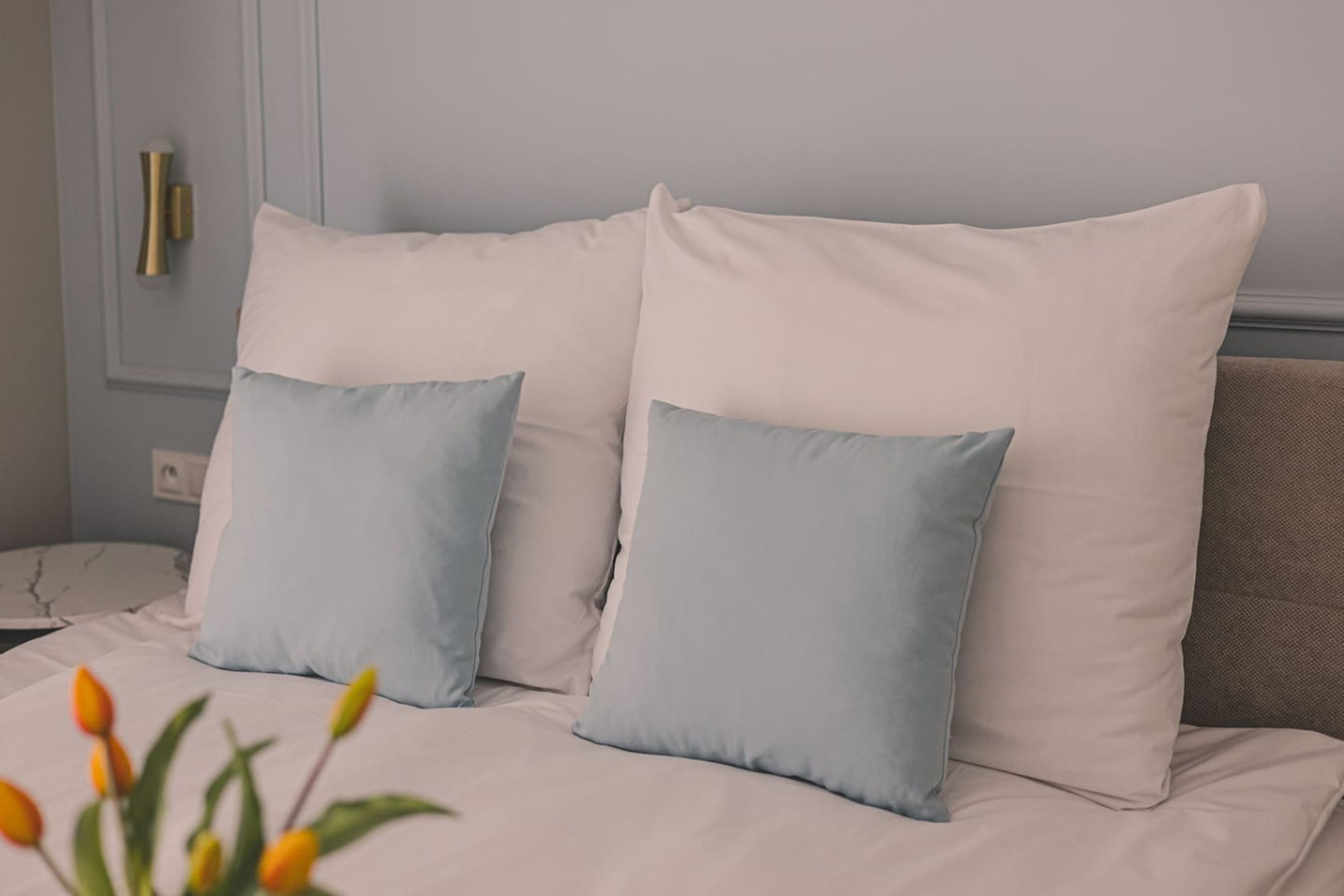 A bed with white bedding and two light blue pillows.