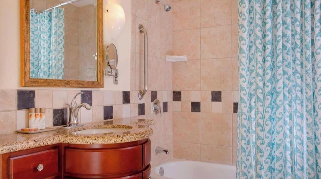 Un baño con lavamanos, espejo y ducha.