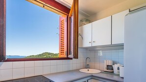 Une cuisine avec vue sur la mer, comprenant un évier, une cuisinière et des placards.