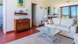 Un salon moderne avec une table basse en verre, un canapé blanc et un meuble en bois.