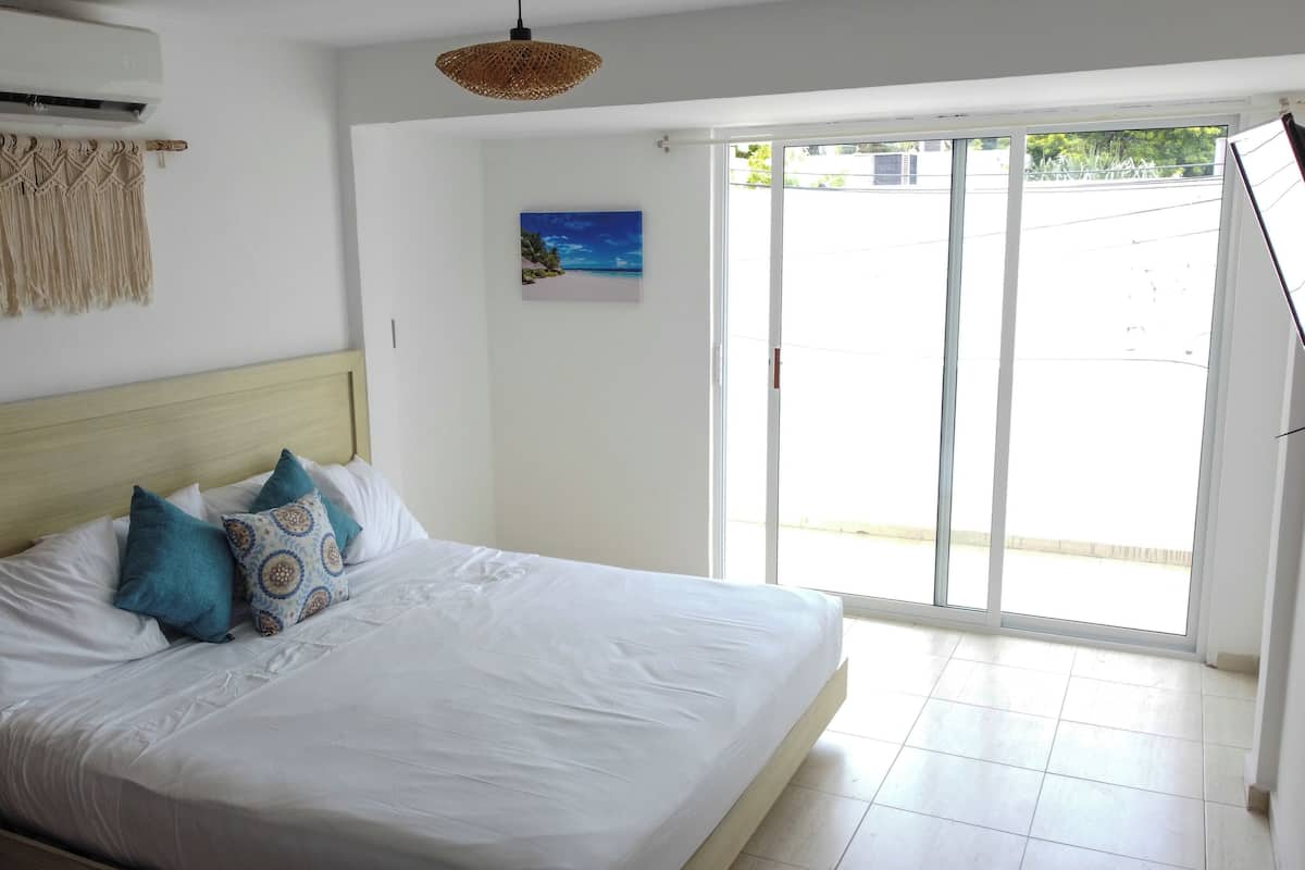 Una camera da letto con un letto, una tenda in macramè, un quadro e vista dalla finestra.