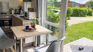 A modern kitchen with a dining area, large windows, and a view of the garden.