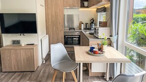 A modern kitchen with wooden cabinets, a built-in oven, a microwave, and a large window offering a view of greenery outside.