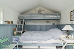 Ein Etagenbett mit einer Leiter, ein Schreibtisch mit Lampe sowie ein Stuhl.