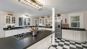 Una cocina moderna con armarios blancos, encimera negra, estufa a gas y refrigerador de acero inoxidable.
