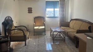 A living room with a sofa, two armchairs, a coffee table, and a window with curtains.