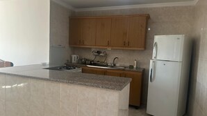 A kitchen with a granite countertop, wooden cabinets, a white refrigerator, and a gas stove.