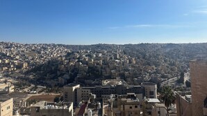 A cityscape with densely packed buildings, a prominent tower, and a clear blue sky.