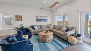 Una sala de estar moderna con un sofá modular, una mesita redonda y un ventilador de techo.