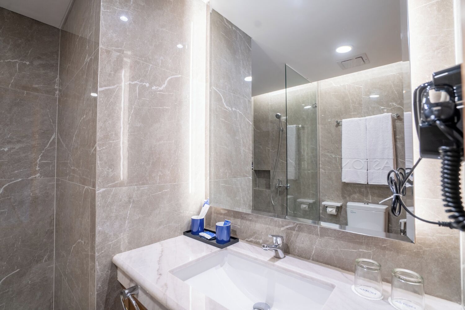 Une salle de bain moderne avec un meuble-lavabo en marbre, une cabine de douche en verre et un téléphone fixé au mur.