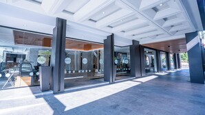 Ein moderner Hotelzugang mit Glastüren, einem Parkplatz und freiem Blick auf die Straße.