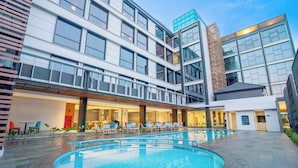 Ein modernes Hotel mit Poolbereich, mehreren Etagen und einer Fassade aus Glas und Backstein.