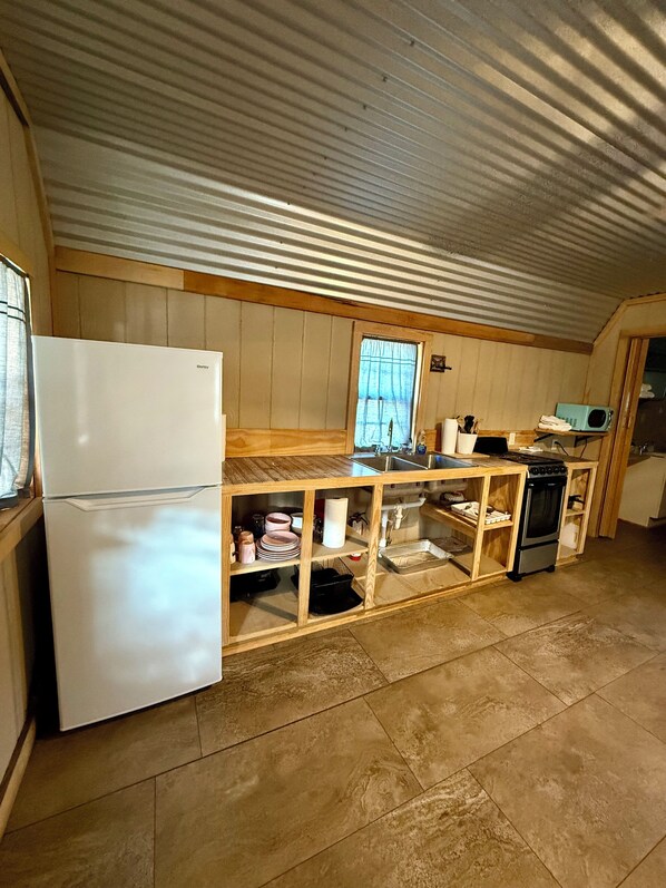 Una cucina compatta con frigorifero, fornello, microonde e mobili in legno.