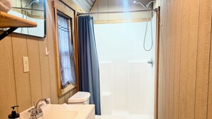 A compact bathroom with a sink, toilet, and shower.