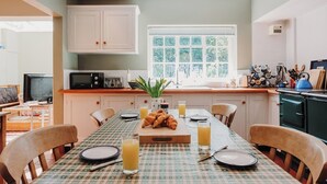 A cozy kitchen with a dining table set for breakfast, featuring croissants, juice, and a toaster.