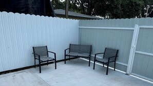 Un espace patio avec trois chaises et une clôture blanche en bois.