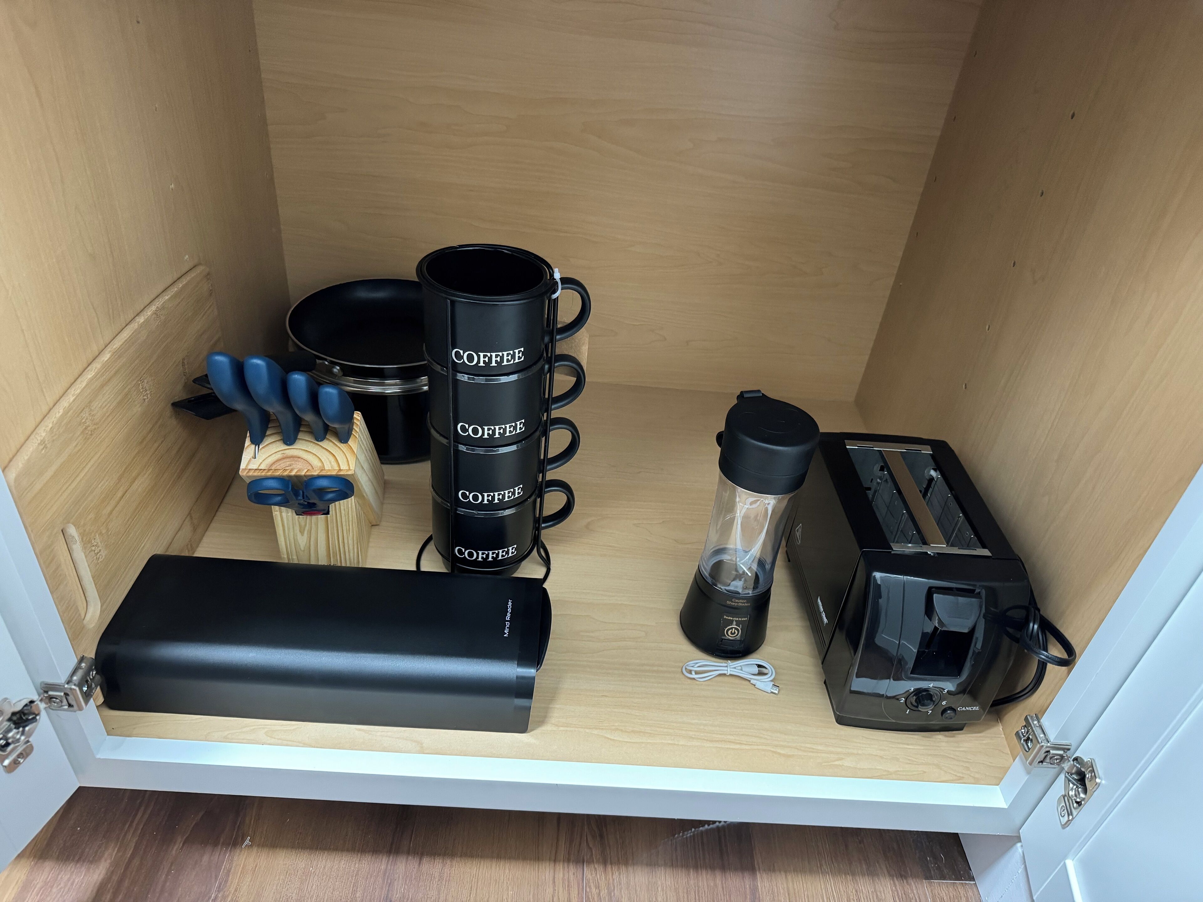 Een keukenhoek met een koffiezetapparaat, een broodrooster, een blender en een set messen op het aanrecht.