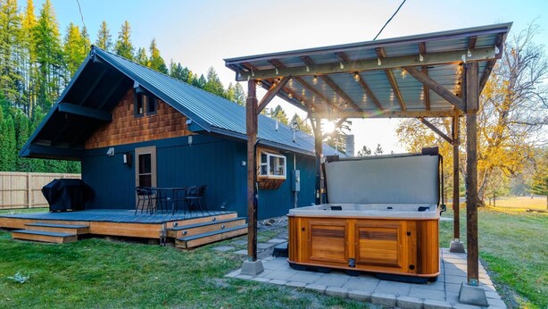 A wooden cabin with a covered deck and a hot tub.