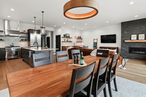 A modern kitchen with a central island, stainless steel appliances, and a dining area with a wooden table and chairs.