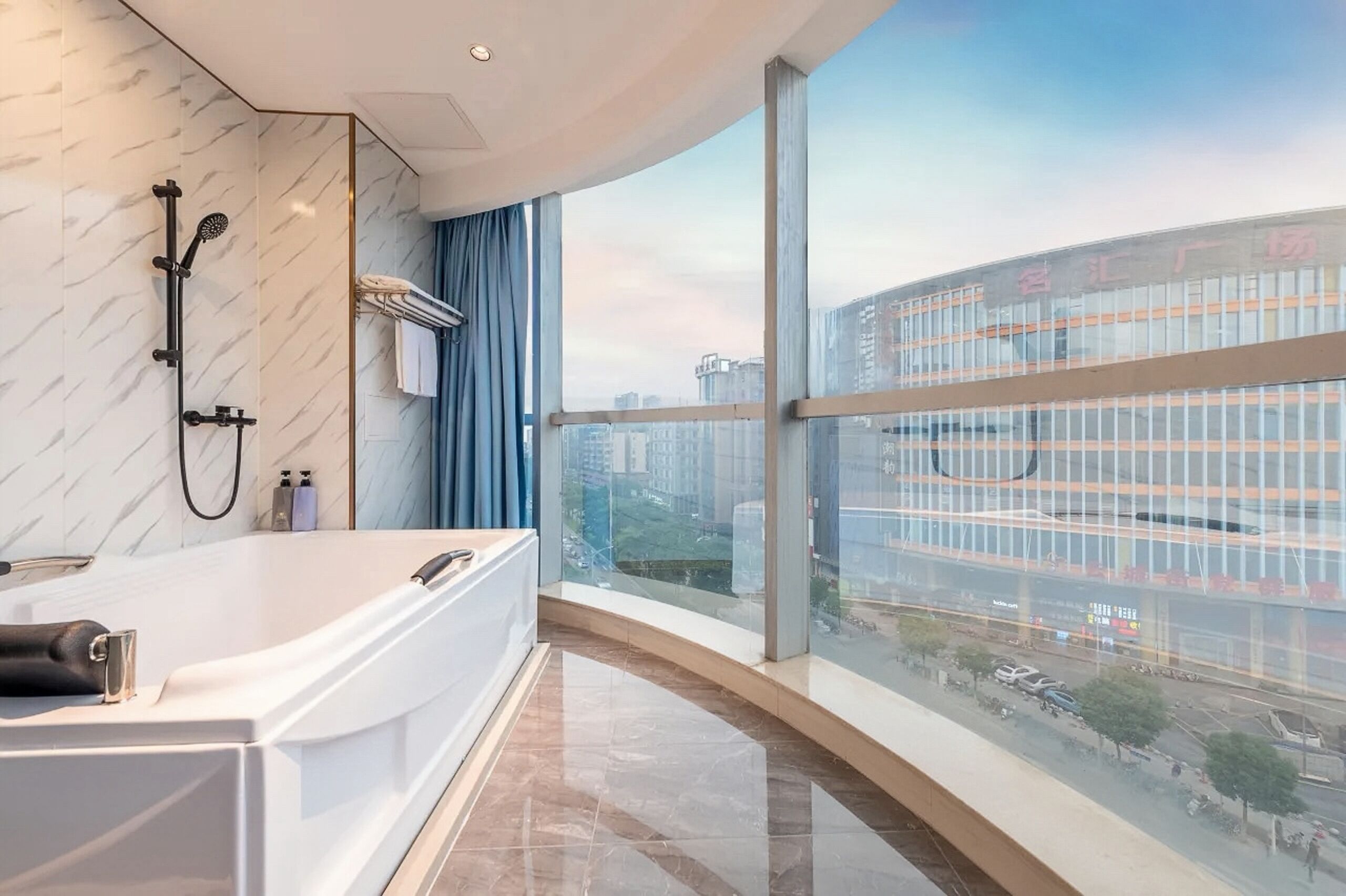 A modern bathroom with a bathtub, shower, and large window overlooking a cityscape.