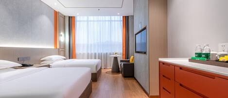 A hotel room with two beds, a small table, a TV, and a minibar.