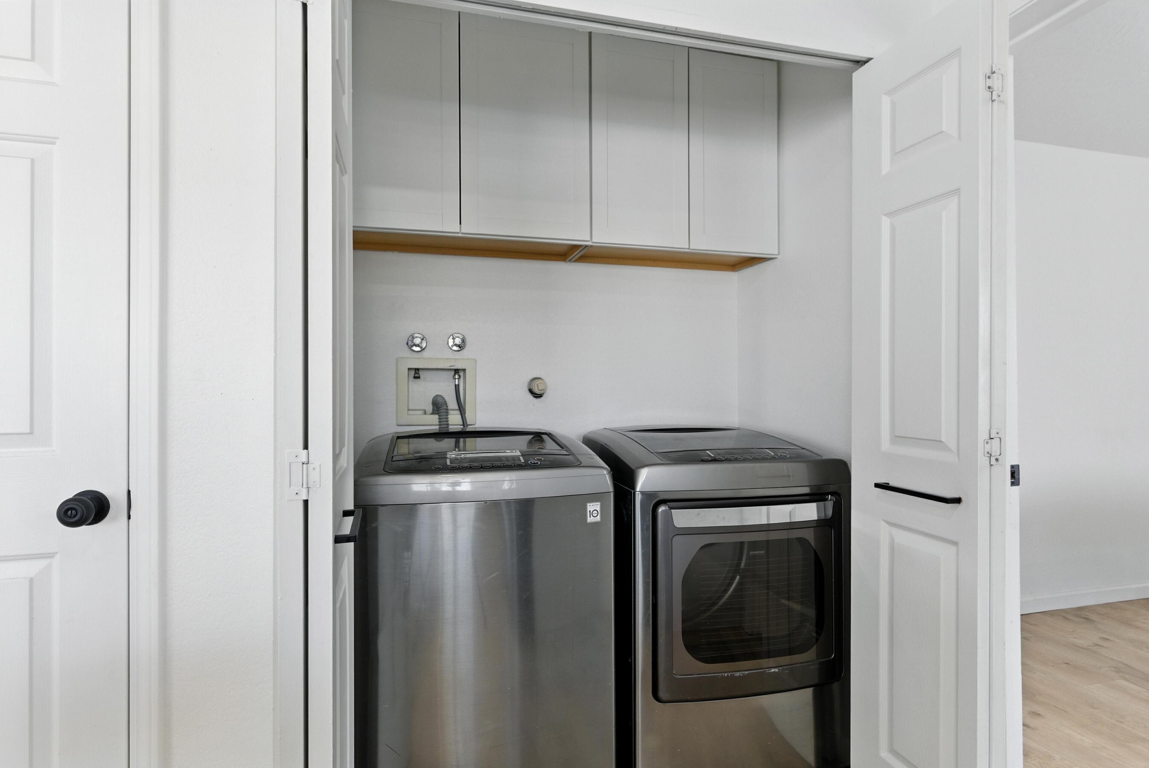 Una cocina compacta con electrodomésticos de acero inoxidable, armarios blancos y horno empotrado.