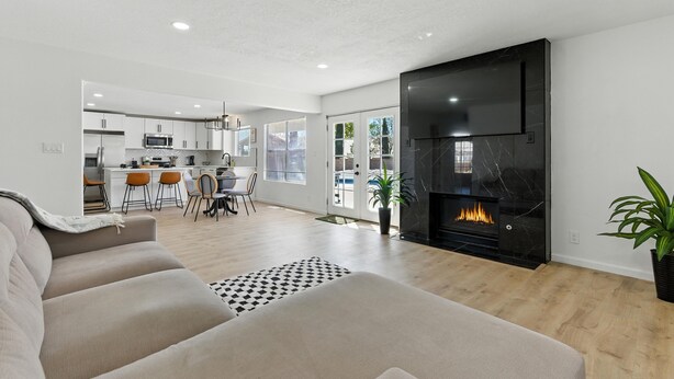 A modern living room with a fireplace, a sofa, and a dining area with chairs and a table.