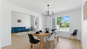 A spacious living area with a dining table, chairs, and a blue sofa.