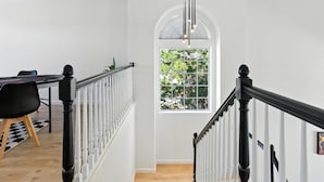 A staircase with white railings and black balusters leading to a room with a large window.