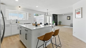 A modern kitchen with white cabinetry, a central island, and two bar stools.
