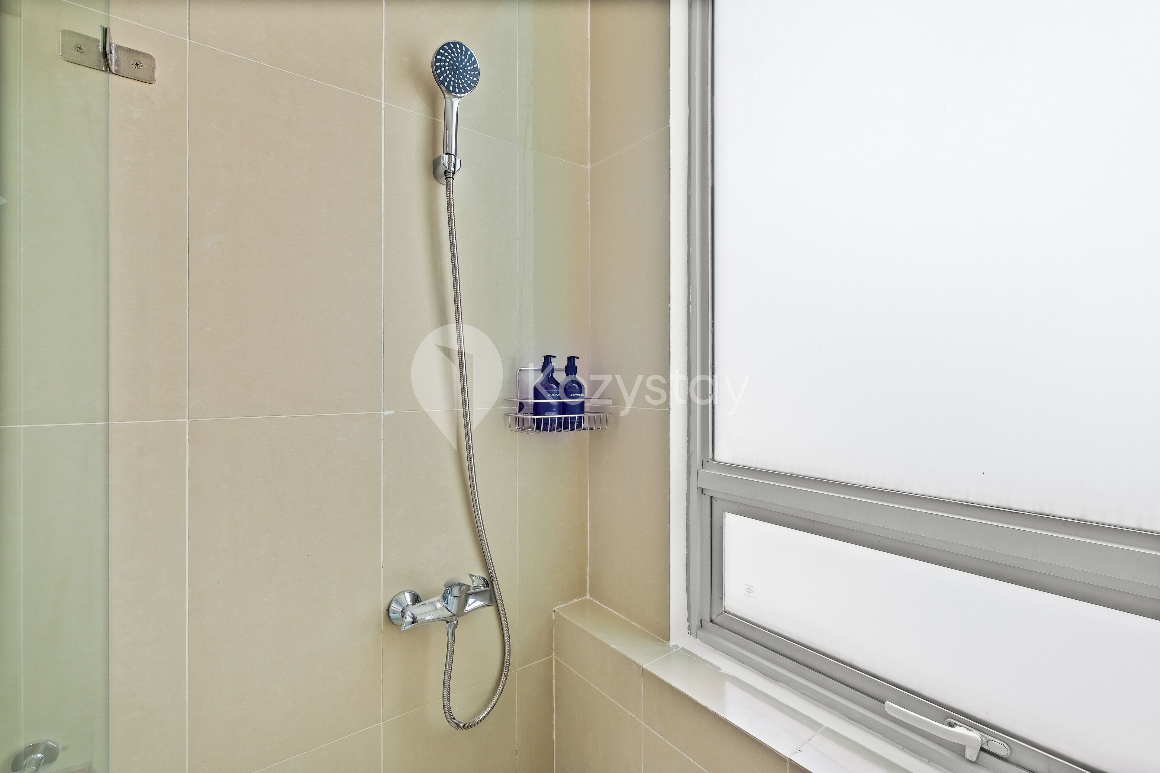 A bathroom with a shower, a window, and a shelf with toiletries.