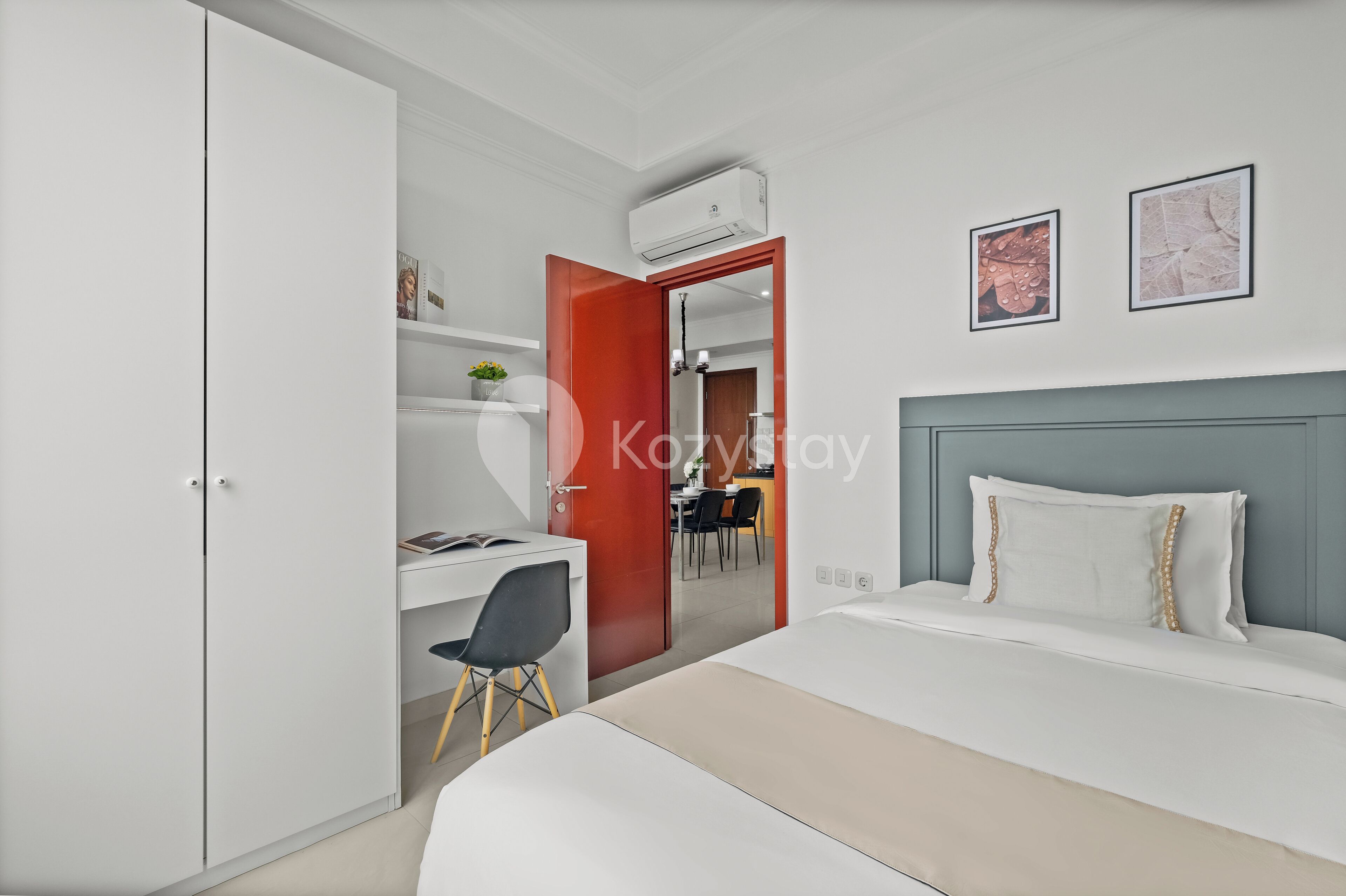A modern hotel room with a bed, a desk, and a wardrobe.