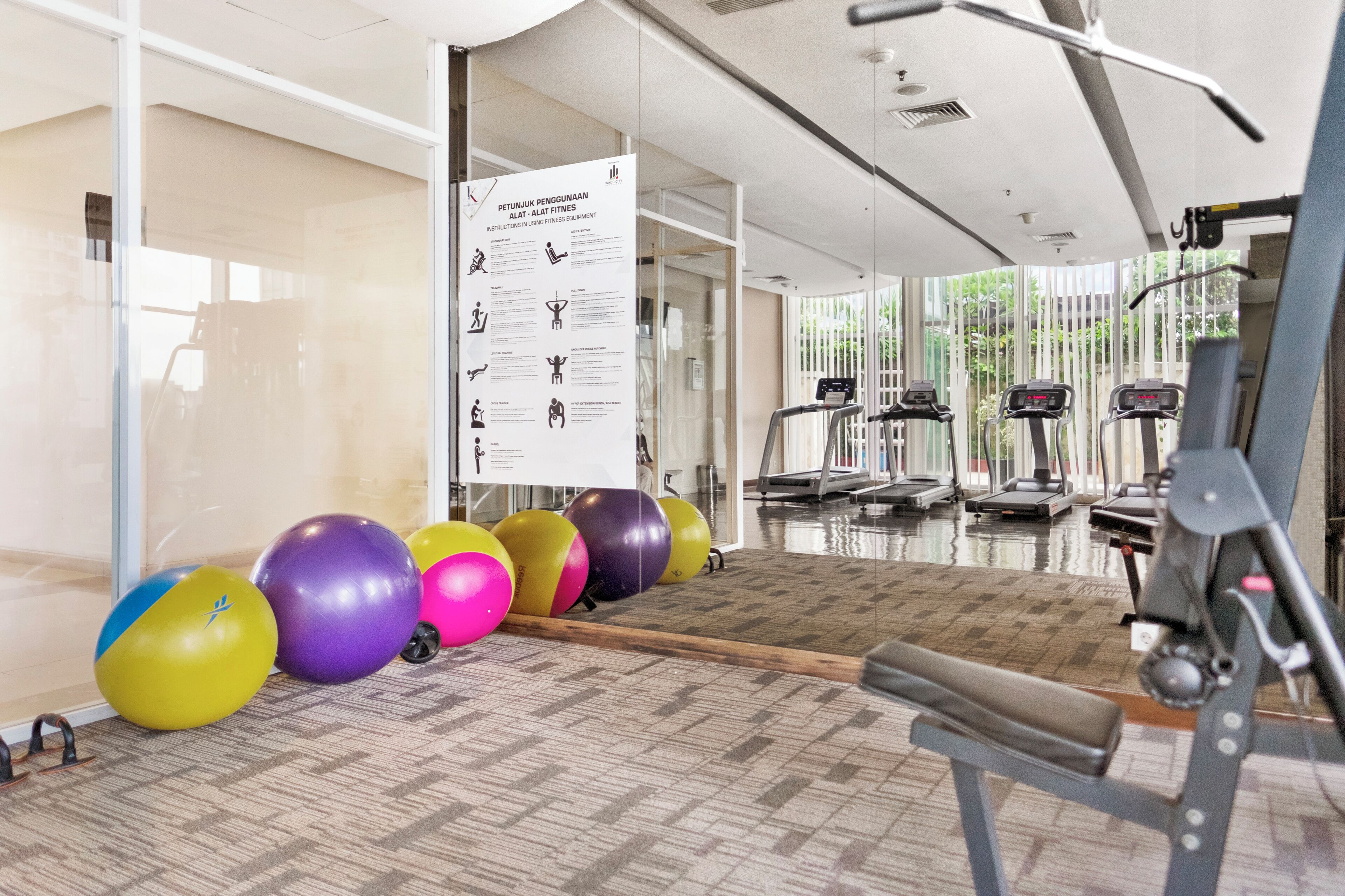 A gym with exercise equipment, a bulletin board with instructions, and exercise balls.
