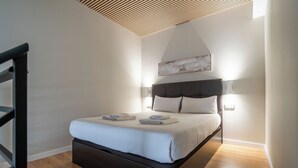 A modern bedroom with a bed, a wooden floor, a wall-mounted light, and a ceiling with a slatted design. - VLC HOST - Sumsi G (Valencia)