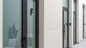 A modern building facade with glass doors marked with letters, a clean, neutral color palette, and a minimalist design. - VLC HOST - Sumsi G (Valencia)