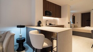 Une chambre d’hôtel moderne équipée d’une kitchenette, d’un canapé et d’un lit.