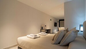 Une chambre moderne avec un grand lit, deux tables de chevet, un téléviseur à écran plat et un petit bureau avec une chaise.