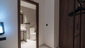 Un couloir avec une armoire en bois, un lavabo blanc et des toilettes au fond.